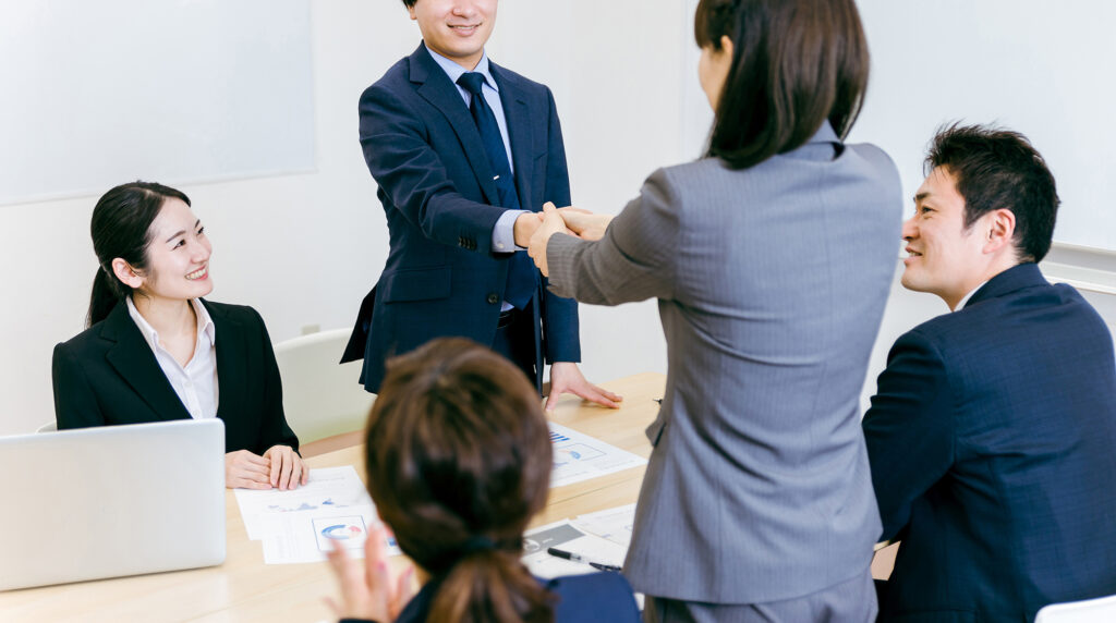 商談で契約して握手するスーツ姿の男女