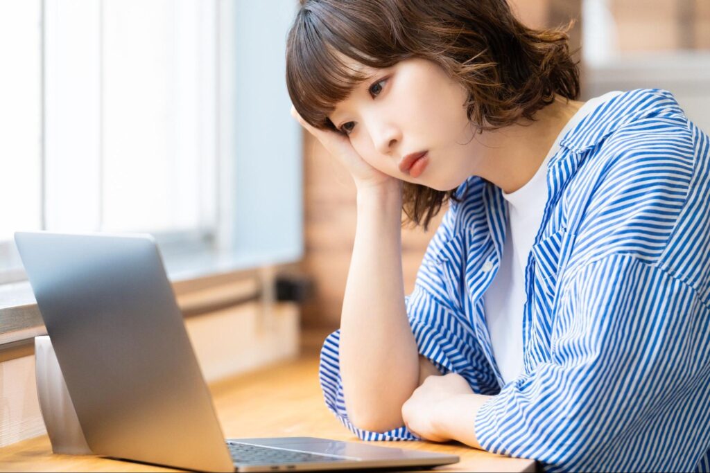 ノートパソコンの前で頭を抱える女性