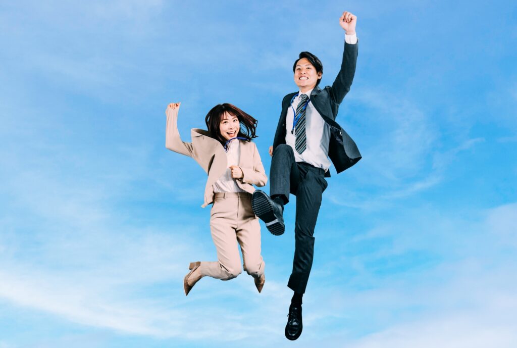 夏の青空にジャンプする男女のビジネスマン