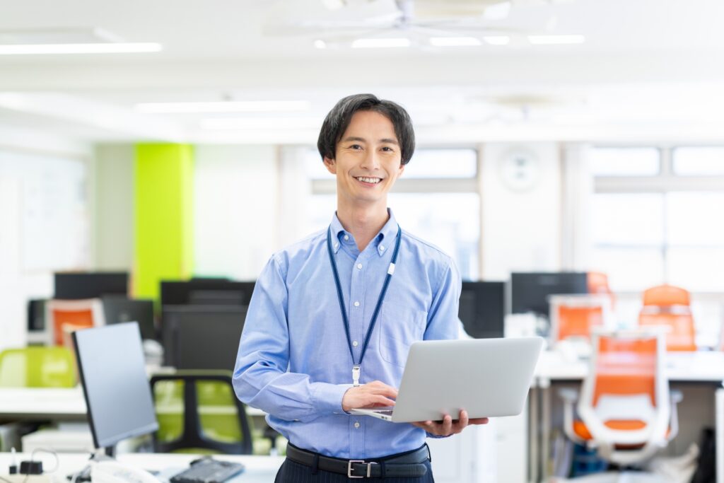 笑顔でノードパソコンを持つ男性