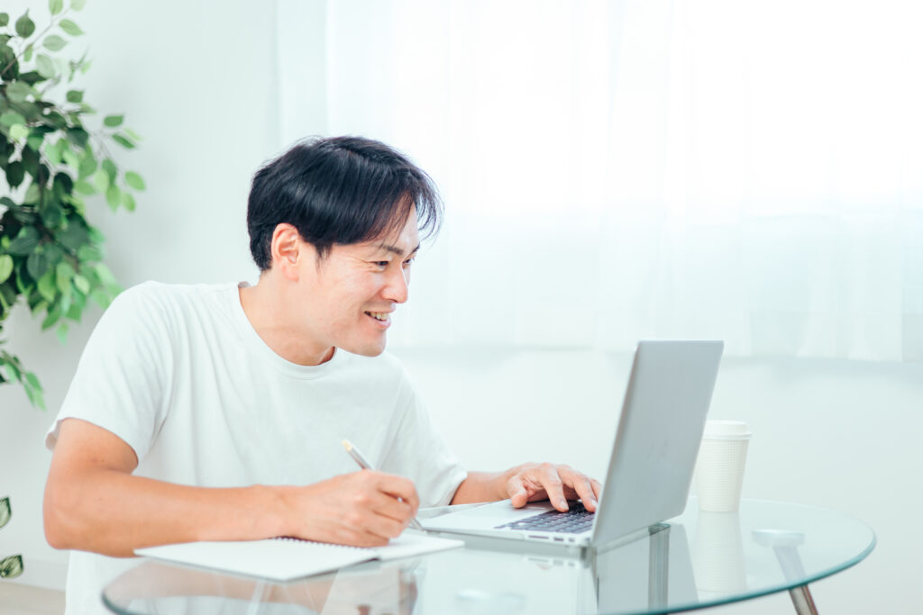 家でパソコンを使って勉強する男性