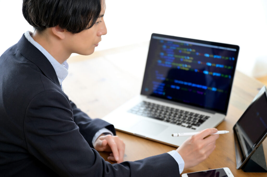 ノートパソコンとタブレット端末を使って仕事をする男性