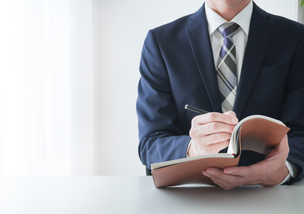 デスクで手帳に記入するビジネスマン