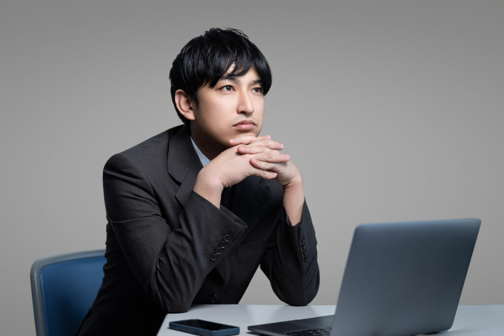 パソコンを使いながら悩む男性
