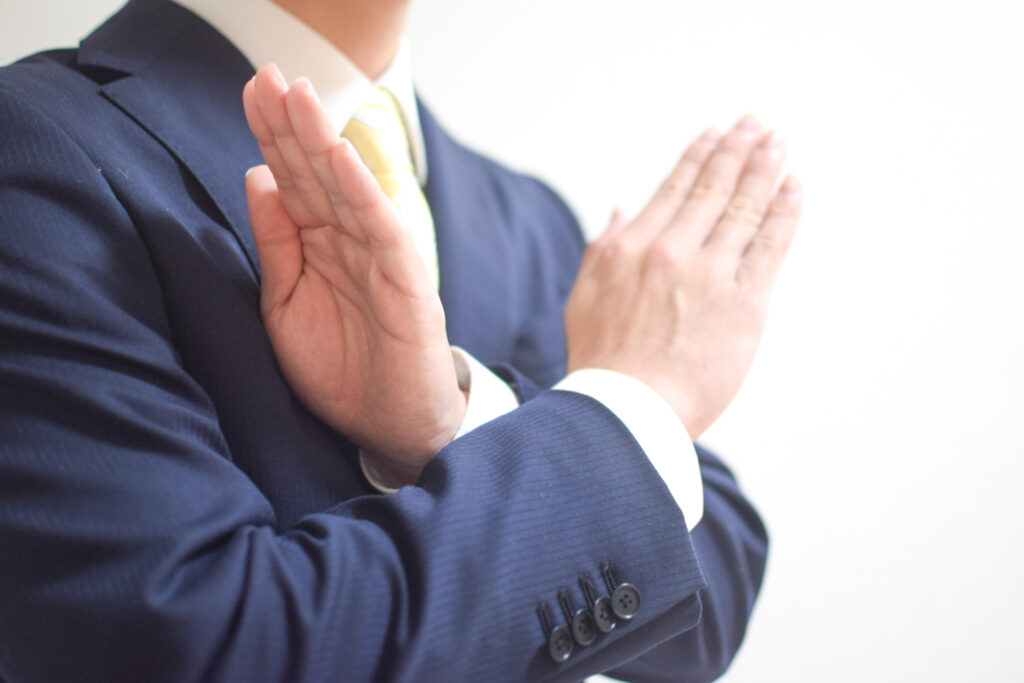 バツマークをするスーツ姿の男性