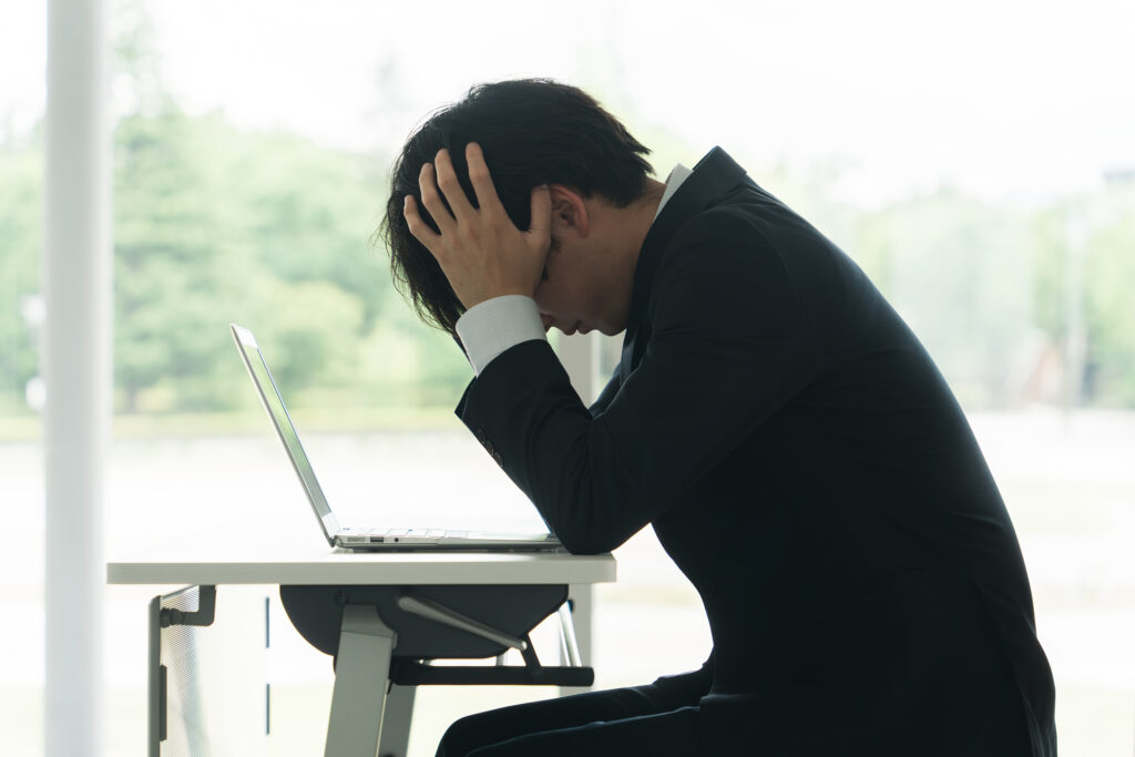 デスクで頭を抱え悩む男性ビジネスマン