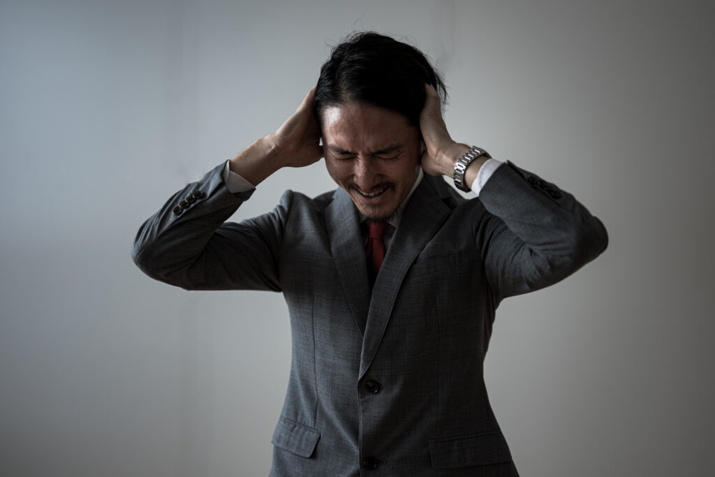 頭を抱えるスーツの中年男性