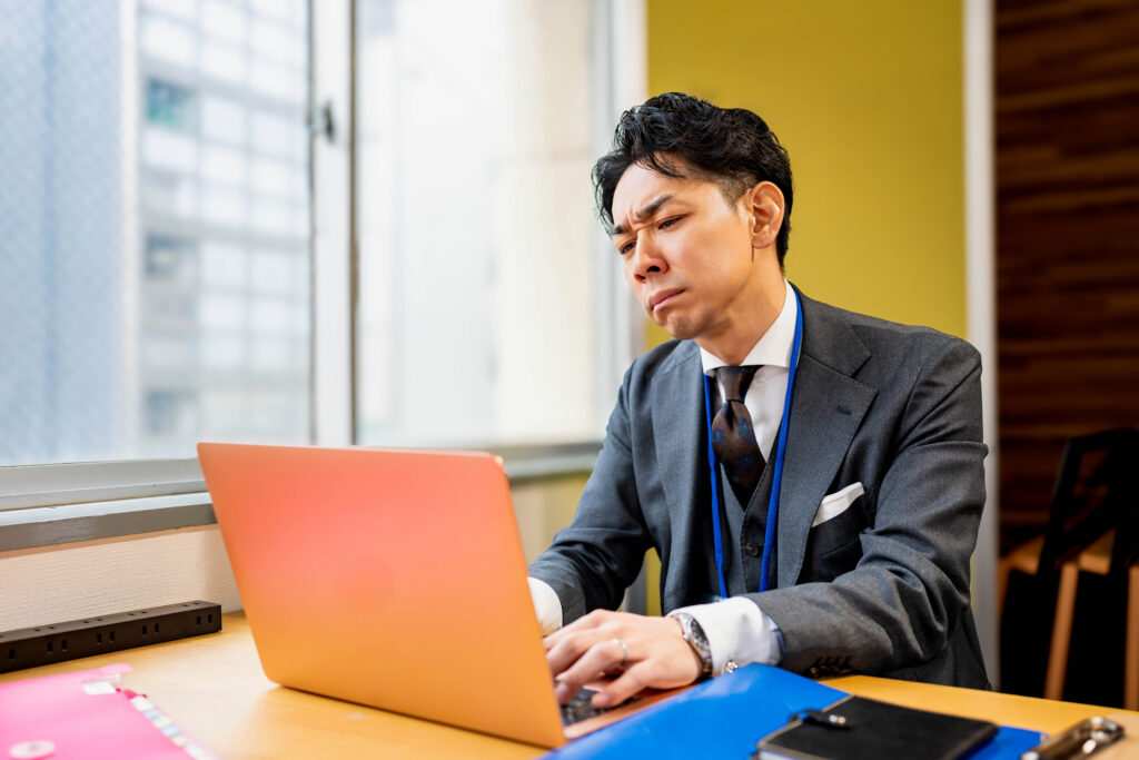険しい顔をしながらパソコンを打つ男性