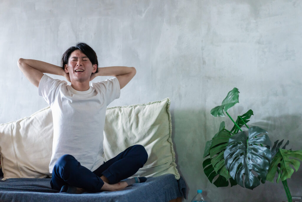 ベッドで伸びをする若い男性
