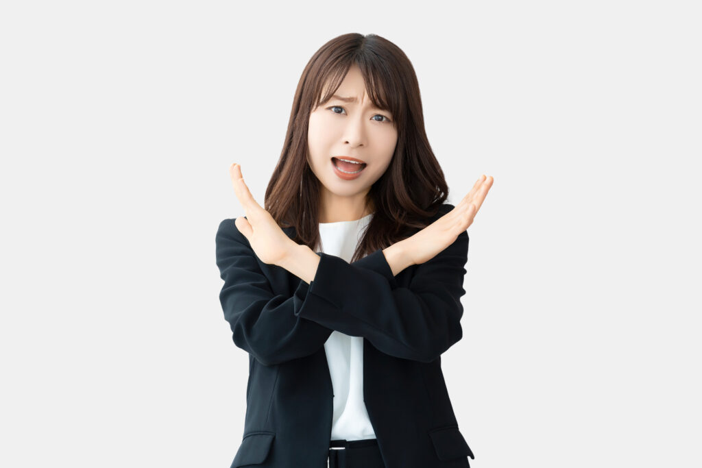 手でバツのポーズをして怒る女性