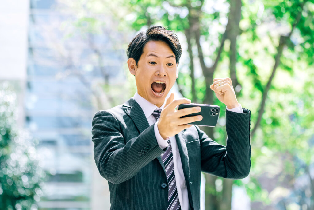 スマホの画面を見て喜ぶ男性
