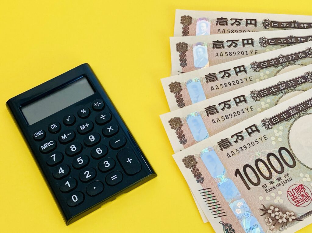 1万円札5枚と黒い電卓(イエロー背景)