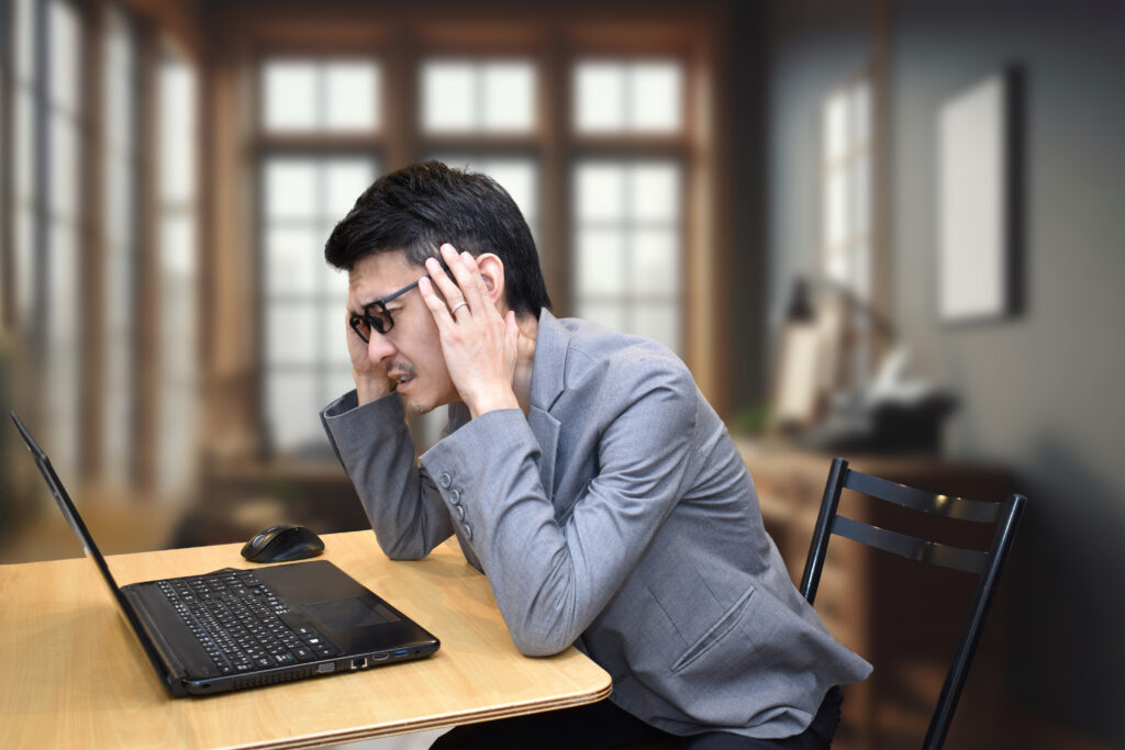 PCの前で頭を抱える男性