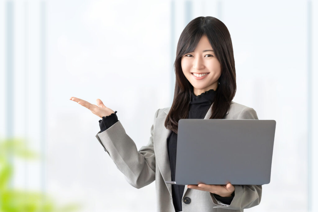 パソコンを持って案内をする笑顔の女性