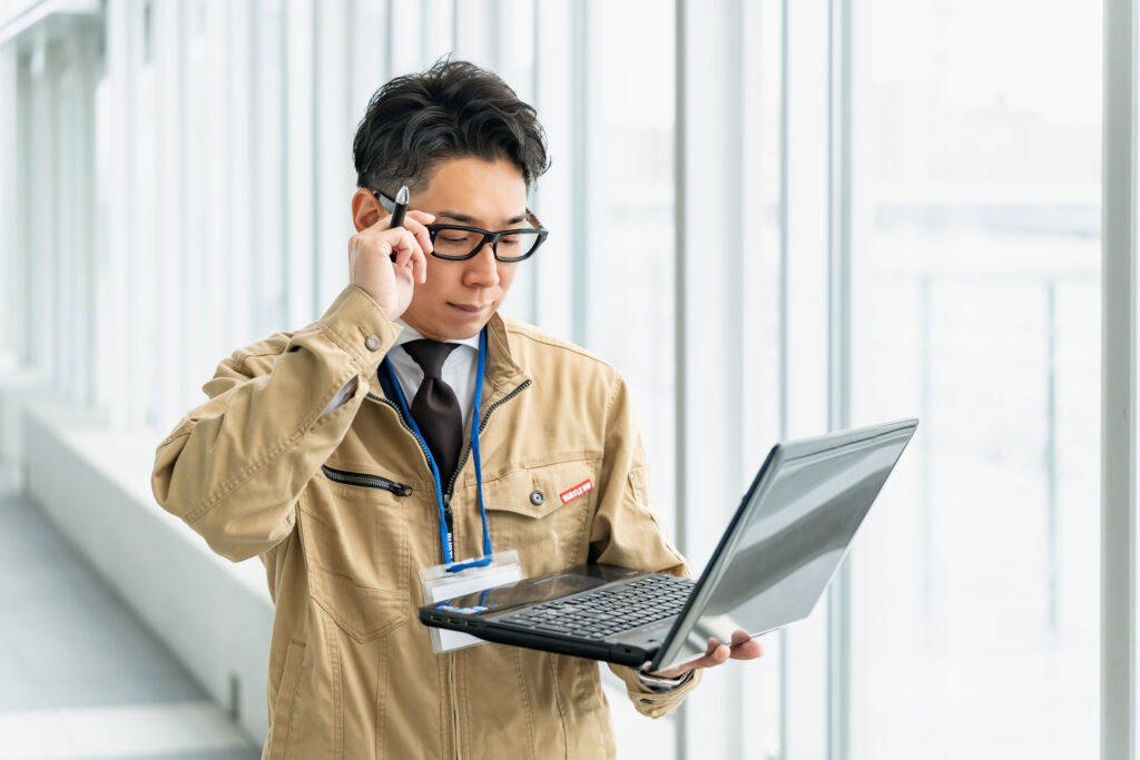 眼鏡を触りながらパソコンを見る作業員