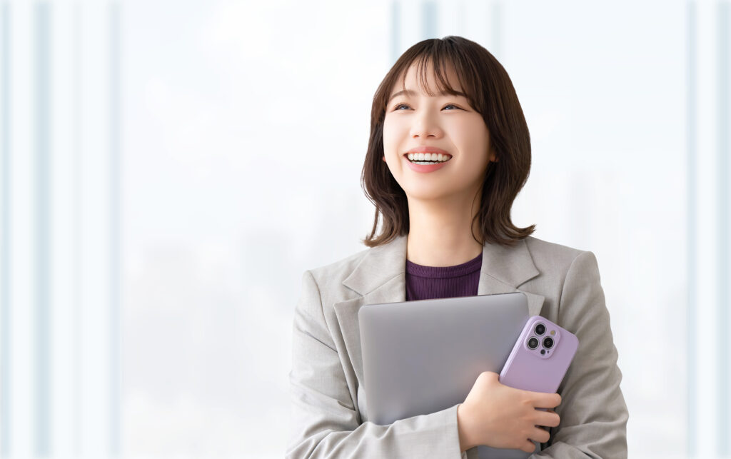 パソコンとスマホを持つ笑顔の女性