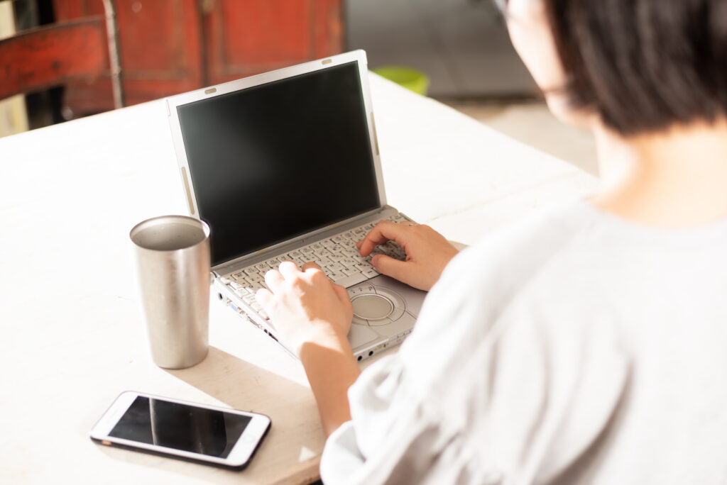 ノートパソコンとスマホを使う女性