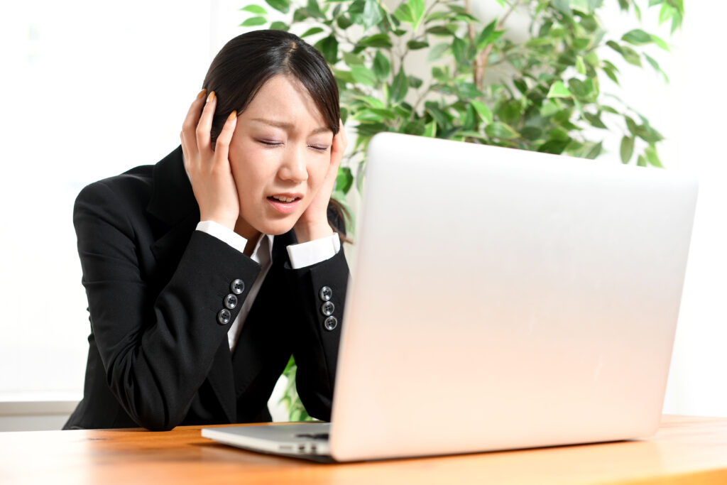ノートパソコンの前で悩むスーツ姿のビジネスウーマンの女性