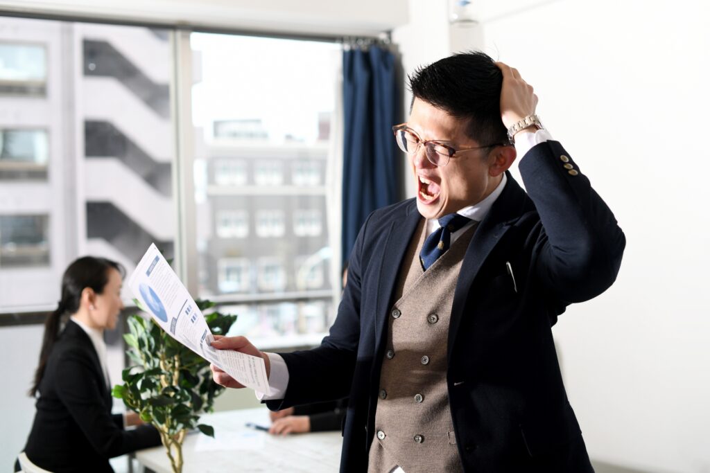 頭を抱えながらショックを受けるビジネスマンの男性
