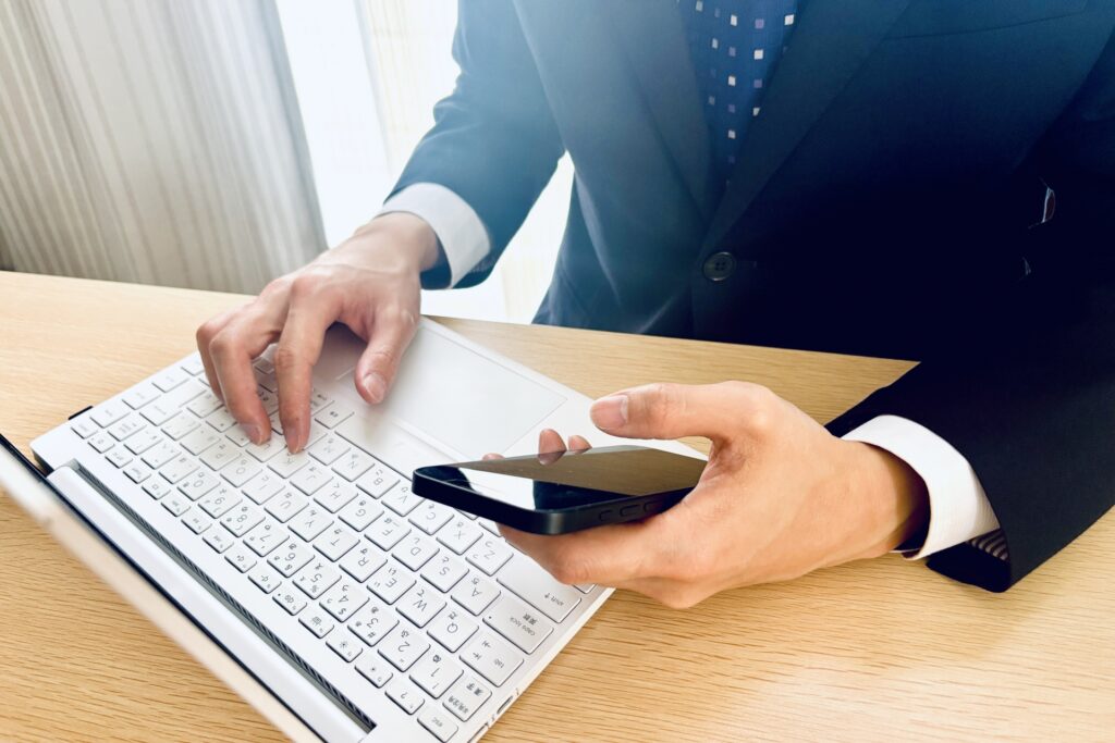 スマホとパソコンで作業するビジネスマン