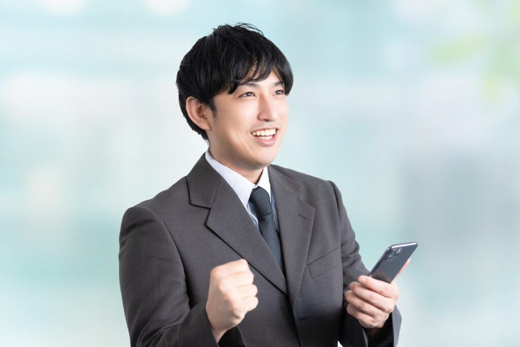 スマホを見て喜ぶ男性ビジネスマン
