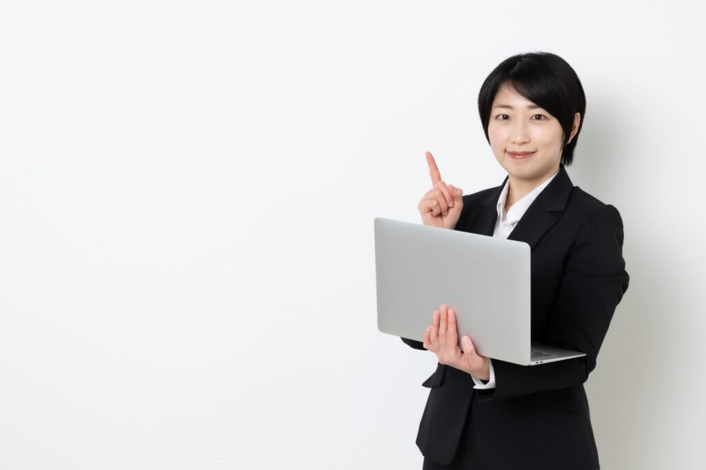 パソコンを持って指差しをしているビジネスウーマン