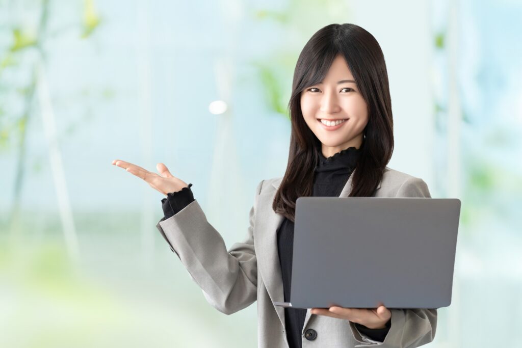 パソコンを持って案内をする笑顔の女性