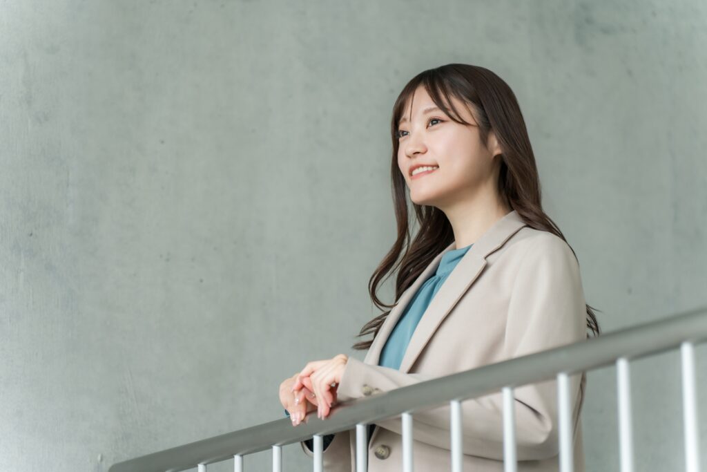 屋内の手すりで外を眺めるビジネスウーマン