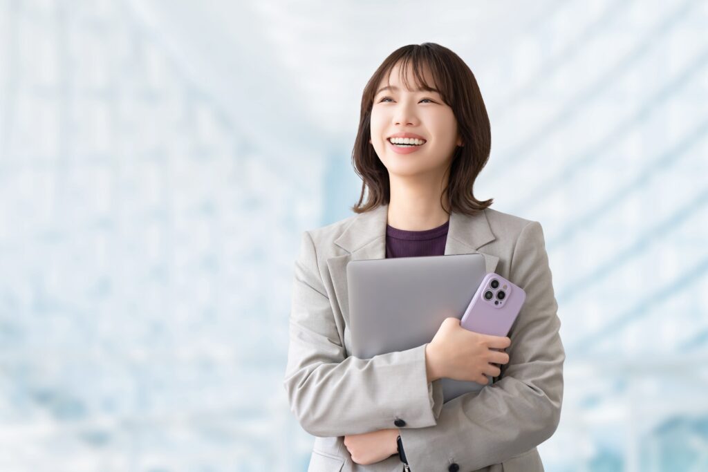 スマホとパソコンを持つ笑顔の女性