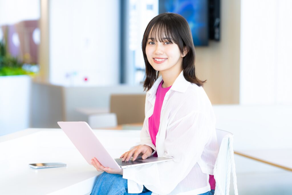 ノートパソコンを膝にのせてほほ笑む女性