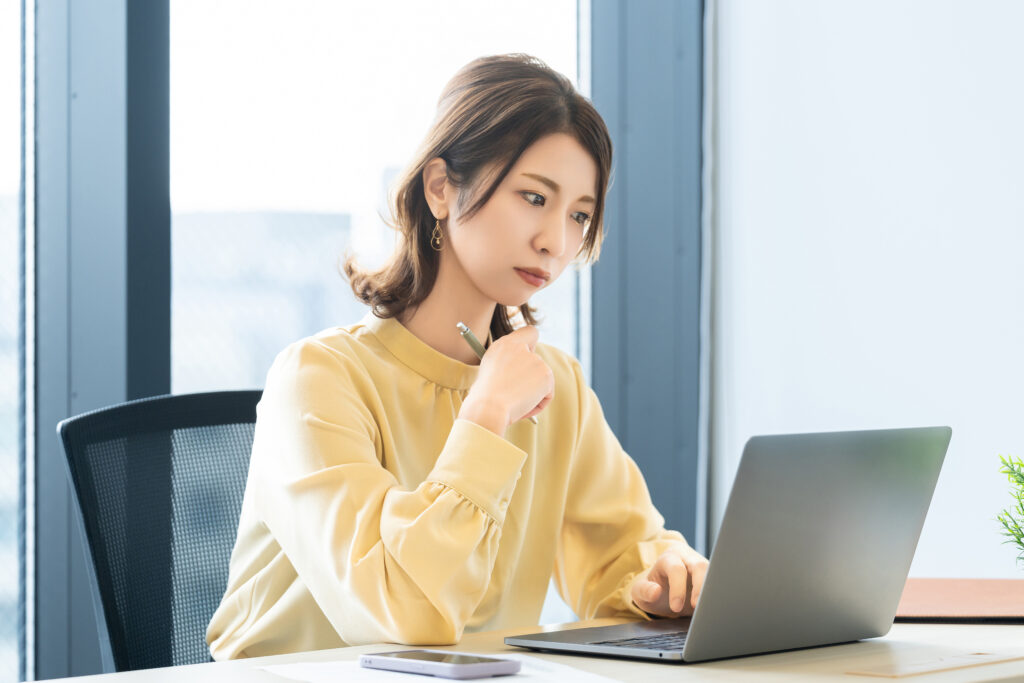 パソコンの画面を見ながら考える女性