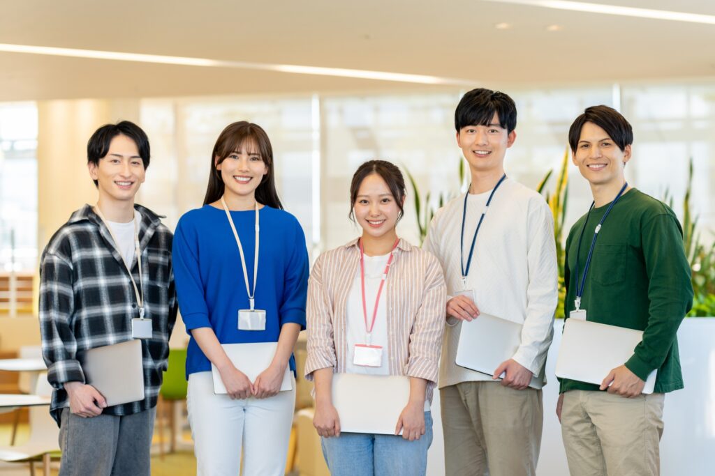 パソコンを持って立つオフィスの人々