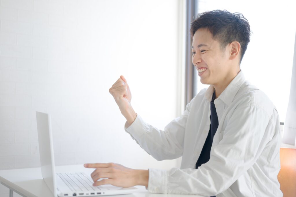 パソコン前でガッツポーズの男性