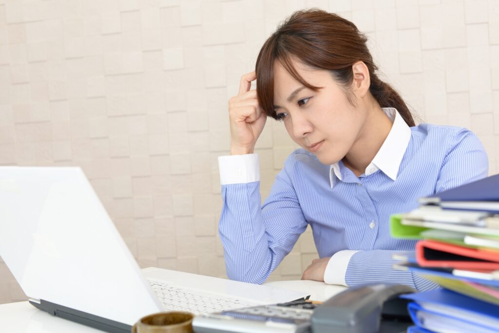 悩むストライプシャツの女性