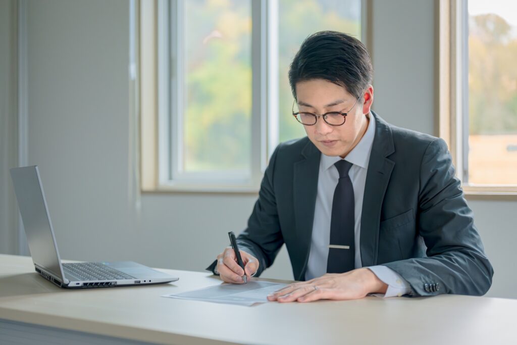書類を書くメガネの男性