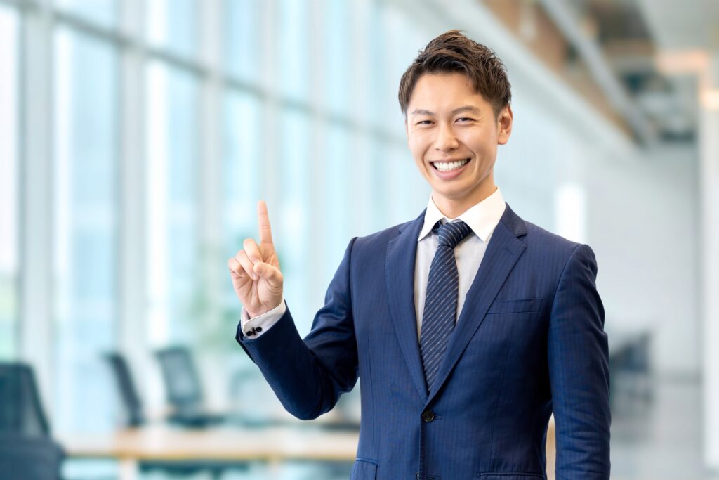 笑顔で人差し指を立てるスーツ男性