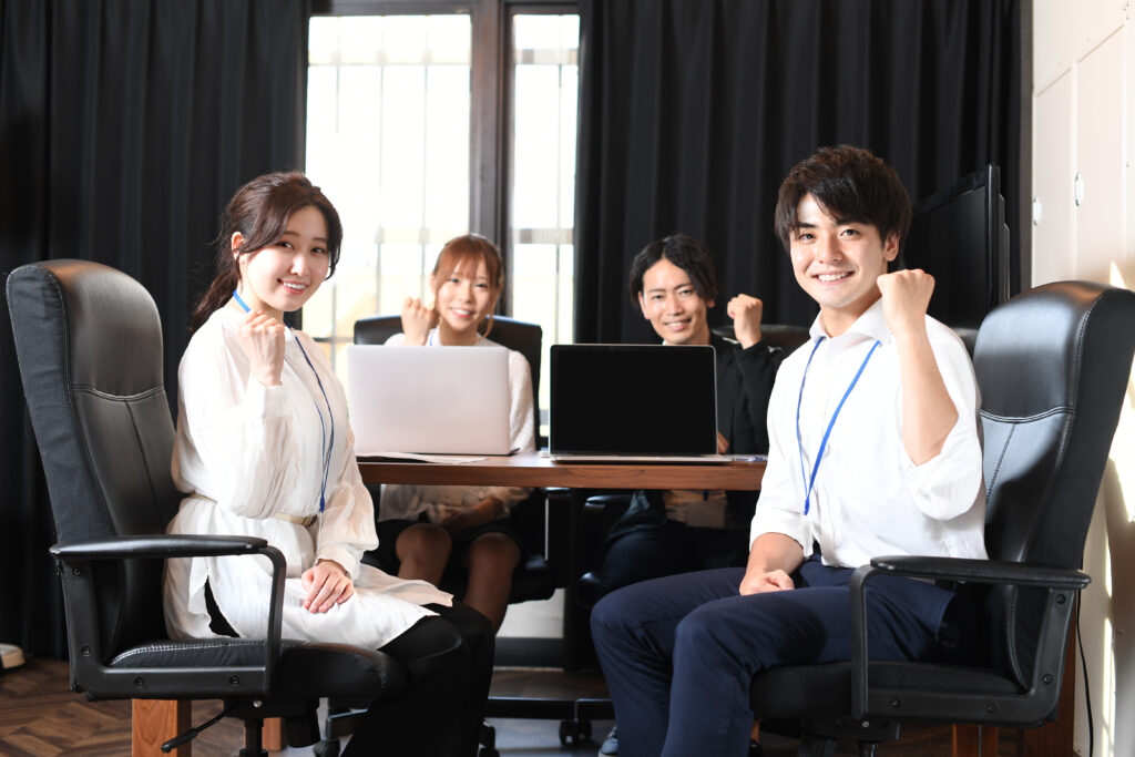 オフィスでガッツポーズをする若いカメラ目線の男性と女性