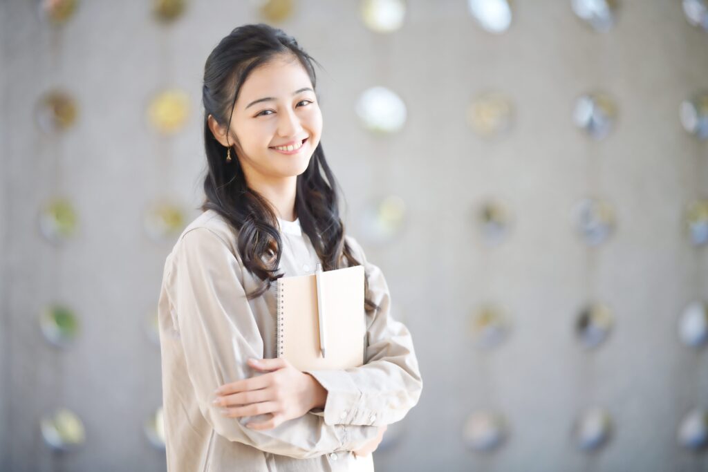 ノートを抱きかかえる笑顔女性