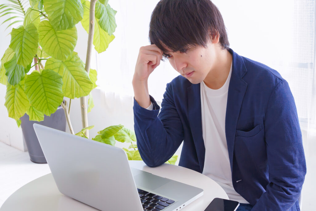 パソコン画面を見て眉をひそめる男性