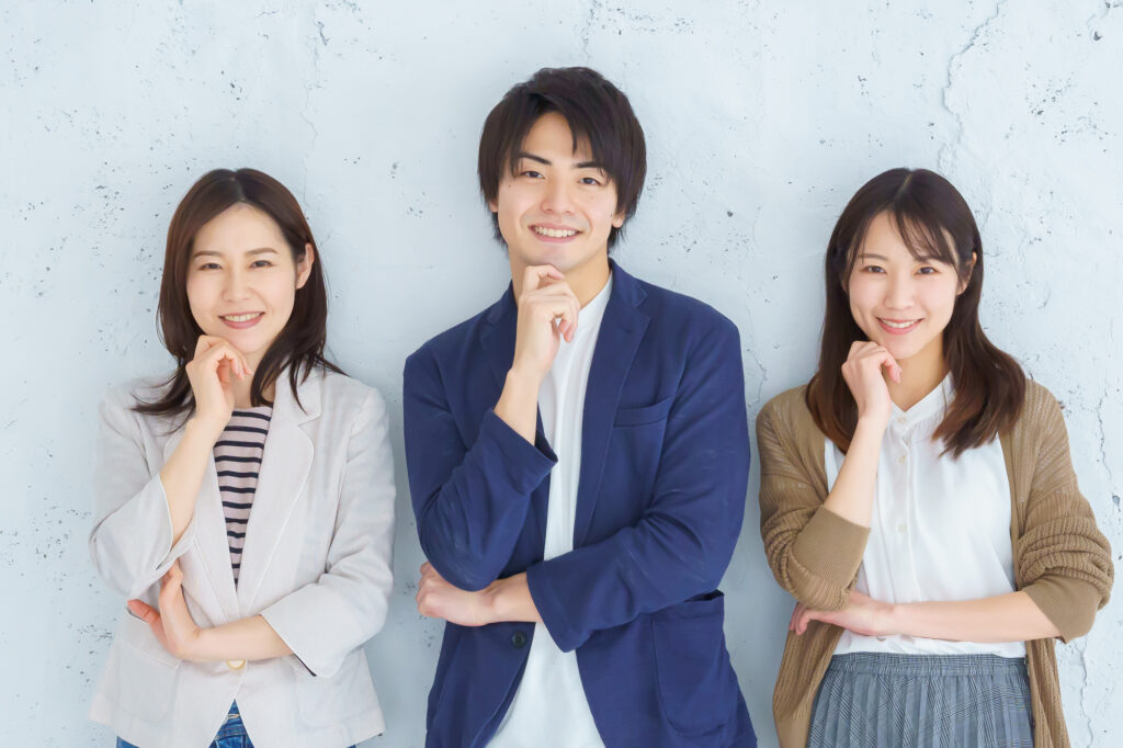 笑顔でこちらを見る3人のビジネスパーソン
