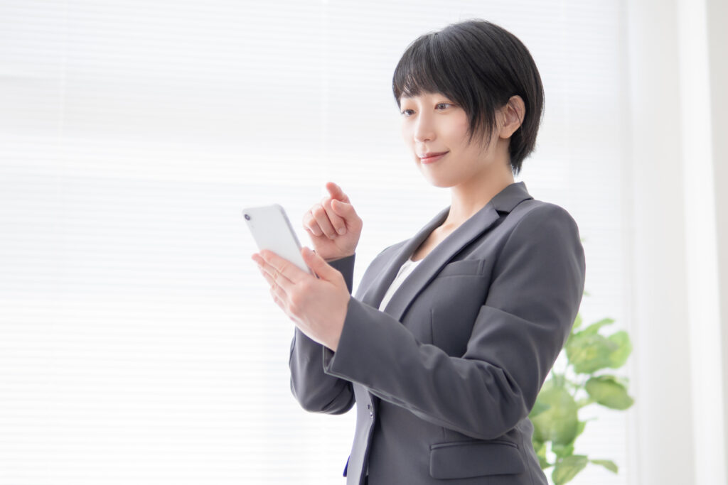 スマホを操作するスーツ姿の女性