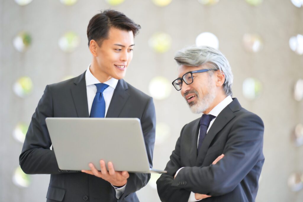 ノートパソコンを見ながら話す上司と部下