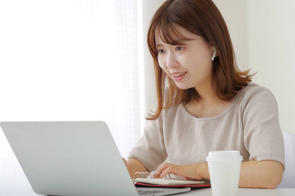イヤホンをつけてパソコンを操作する女性