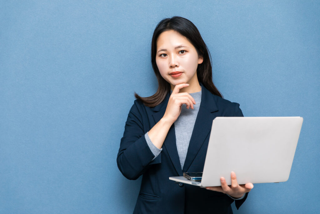 パソコンを持って考えるビジネスウーマン