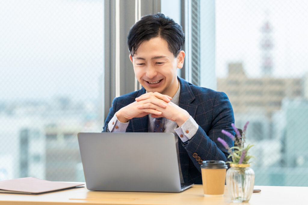 パソコンを使う笑顔の男性ビジネスマン