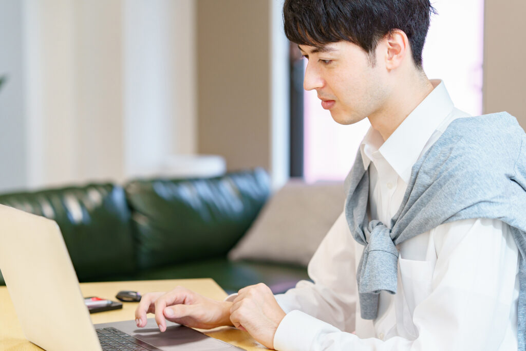 カジュアルな服装でノートPCを使う男性