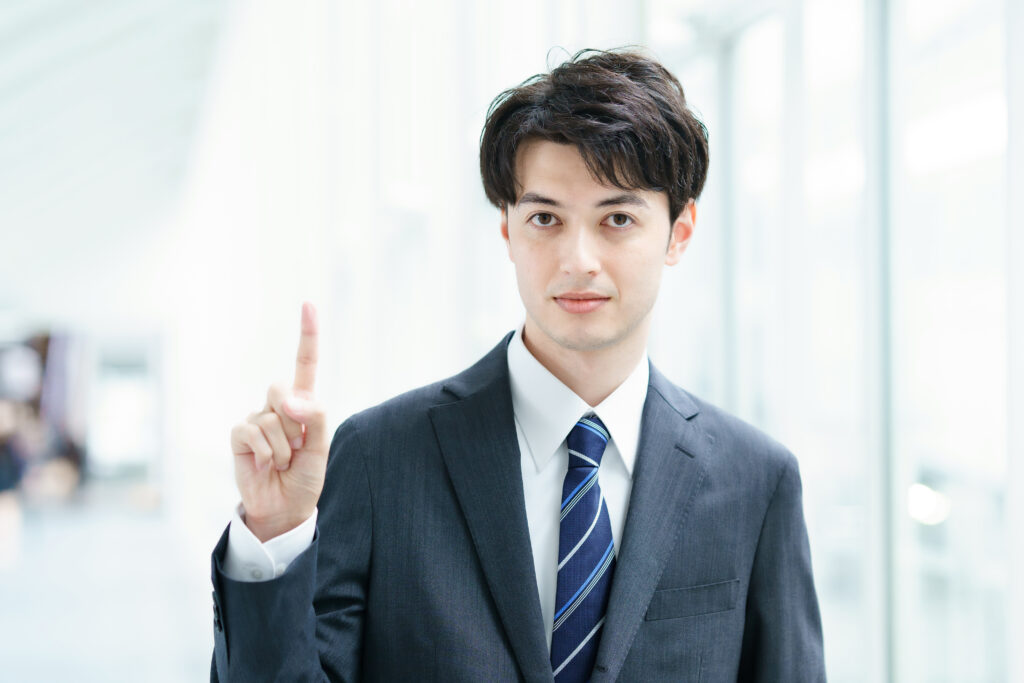 人差し指を立てたポーズのビジネスマ