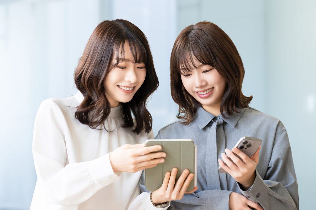 スマホとタブレットを見て話す2人の女性