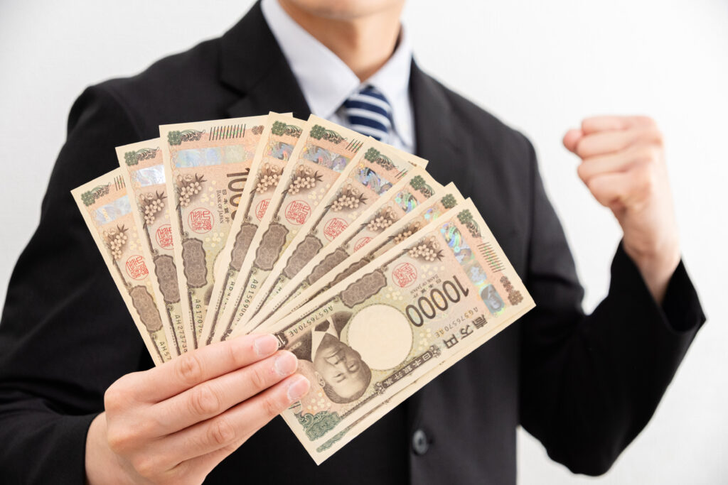 お金を手にガッツポーズするビジネスマン