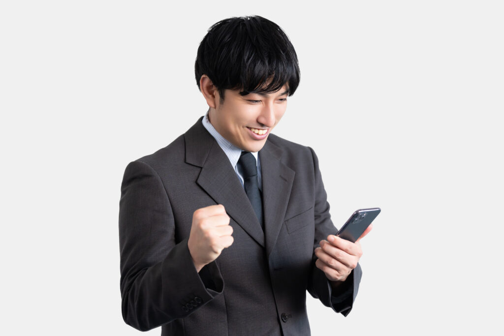 スマホの画面を見て喜ぶ男性ビジネスマン